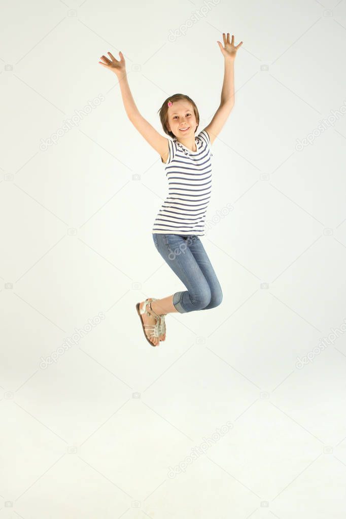 Vertical Portrait Of Jumping Little Girl. Cute Jumping Girl. Cheerful Pretty Young Girl Jumping And Holding Hands Up.