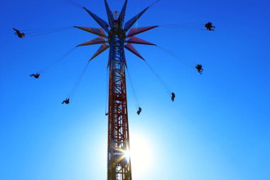 Siluetleri üzerinde bir atlıkarınca Lunaparktaki, insanların aşağıdan görüntüleyin. Eğlence Parkı aşırı bir cazibe kadeh kırpılmış.