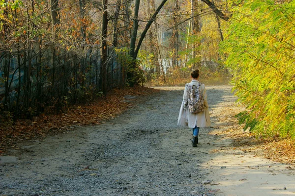 Young woman walking outdoors. Full length portrait of teenage girl walking in the forest, back view.