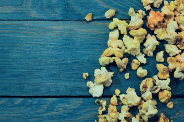 Mavi ahşap arka planda sarı karamelli patlamış mısır. Fast food, abur cubur. Soyut renkli yemek arkaplanı.