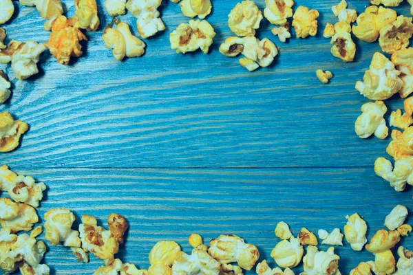 黄色の青い木製の背景にポップコーンをカラメル ファーストフード ジャンクフード 概要カラフルな食品背景 — ストック写真