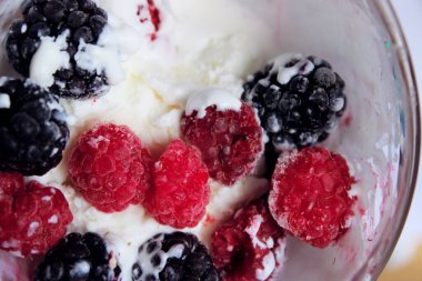Kesilmiş dondurma, kırmızı ahududu ve böğürtlen. Soyut gıda geçmişi. Yoğurt ve böğürtlen, yakın çekim, üst manzara.