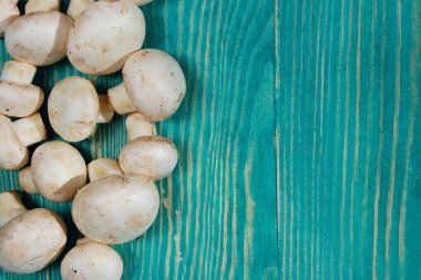 Mavi tahta masada beyaz şampiyonlar var. Ahşap arka planda mantarlar. Yiyecek konsepti.