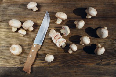 Tahta saplı çelik bıçak ve tahta bir masada kesilmiş şampiyonlar. Mutfak, yemek pişirme konsepti.