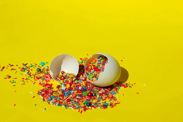 黄色の背景に壊れた白い卵の殻の中の小さな多色のお菓子 イースター 食品の概念 カラフルな食品の背景を抽象化 — ストック写真