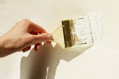 Ahşap arka planda beyaz boyalı fırça tutan bir kadın. İnsanlar, tamirat, sanat konsepti.