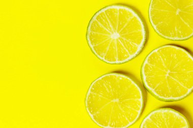 Sarı arka planda dilimlenmiş kireç. Renkli yemek arkaplanı, yatay görünüm.