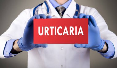Doctor's hands in blue gloves shows the word urticaria. Medical concept. clipart