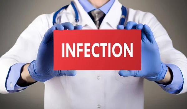 Le mani del dottore con i guanti blu mostrano la parola infezione. Concetto medico . — Foto Stock