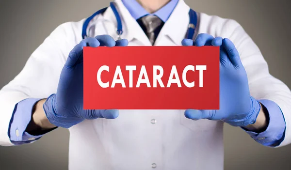 Las manos del doctor en guantes azules muestran la palabra catarata. Concepto médico . — Foto de Stock