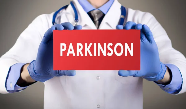 As mãos do médico de luvas azuis mostram a palavra parkinson. Conceito médico . — Fotografia de Stock