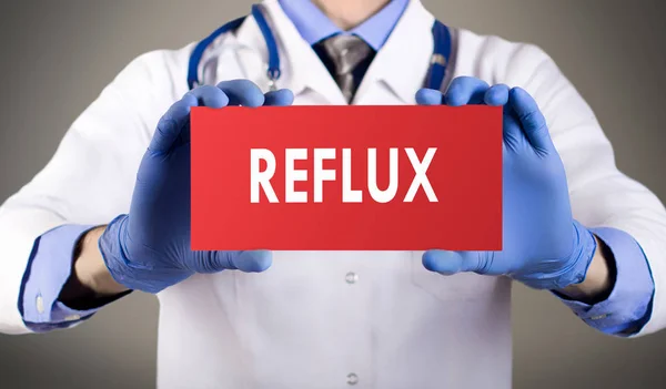Las manos del doctor en guantes azules muestran la palabra reflujo. Concepto médico . — Foto de Stock