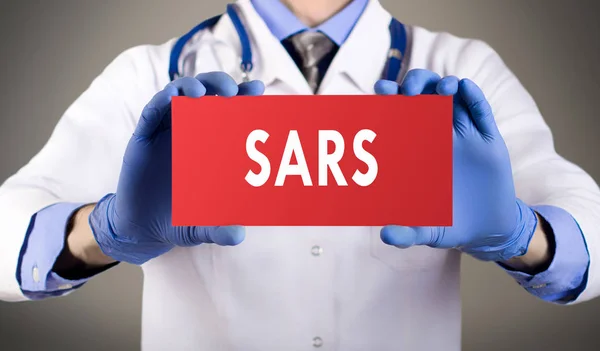 As mãos de doutor em luvas azuis mostram a palavra sars. Conceito médico . — Fotografia de Stock
