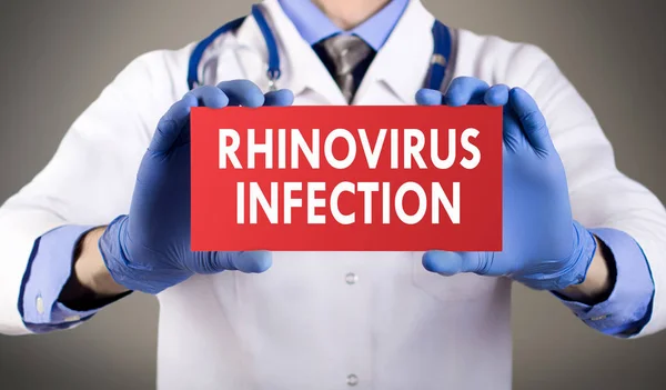 As mãos do médico de luvas azuis mostram a palavra infecção por rinovírus. Conceito médico . — Fotografia de Stock