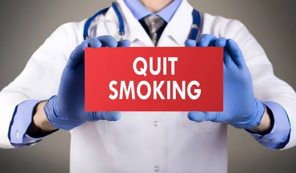 Les mains du docteur en gants bleus montrent le mot cesser de fumer. Concept médical . — Photo