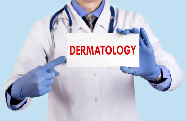 El doctor guarda una tarjeta con el nombre de la dermatología. Enfoque selectivo. Concepto médico . — Foto de Stock