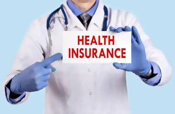 Läkaren håller ett kort med namn av sjukförsäkringen. Selektivt fokus. Medicinska begrepp. — Stockfoto