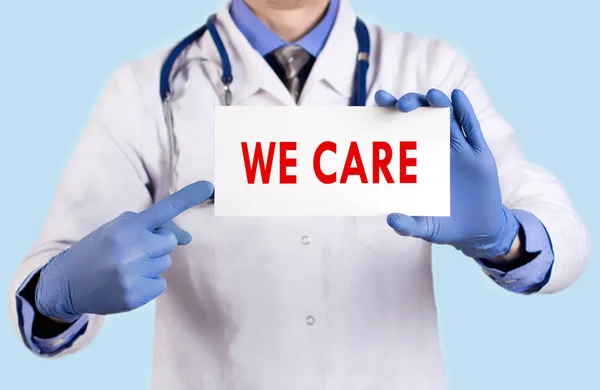 Doctor keeps a card with the name of the we care. Selective focus. Medical concept. — Stock Photo, Image