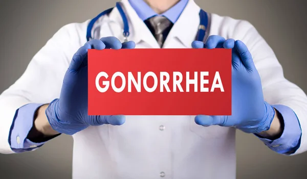 Doctor's hands in blue gloves shows the word gonorrhea. Medical concept. Stock Photo