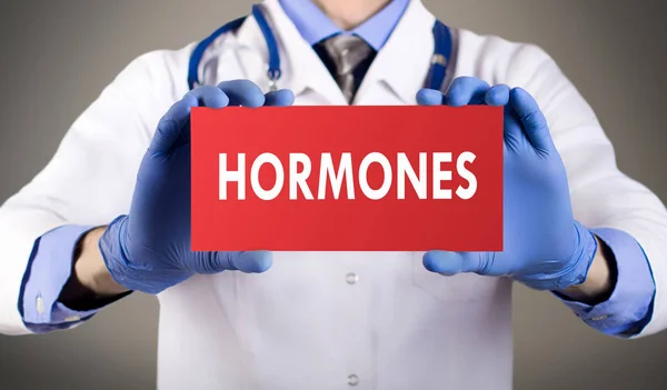 Doctor's hands in blue gloves shows the word hormones. Medical concept. Royalty Free Stock Photos