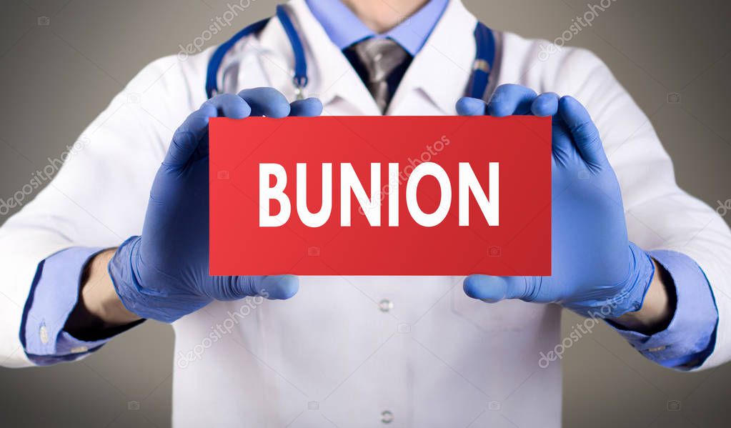Doctor's hands in blue gloves shows the word bunion. Medical concept.