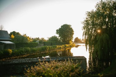 Gün batımında köy ve göl, Güneş