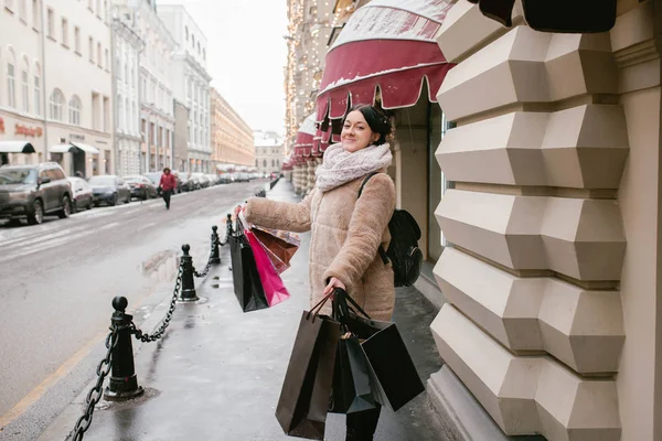 A girl holds many packages on the street. Shopping