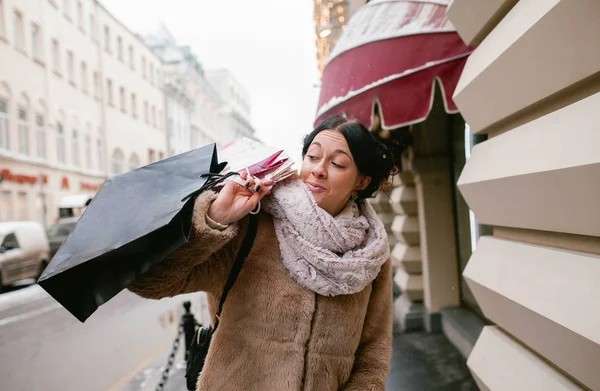 A girl holds many packages on the street. Shopping