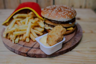 Nuggets peynir soslu, hamburger ve patates kızartması ahşap arka plan üzerinde