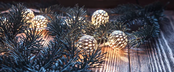 Christmas string lights and fir branches on wooden background. vintage garland and bokeh. — Stock Photo, Image