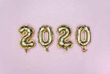 Mutlu yıllar 2020 kutlamaları. 2020 sayılı altın folyo balonlar ve pastel pembe arka planda altın yıldızlar. Düz yatıyordu.