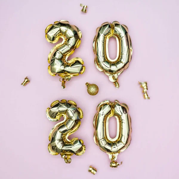 Gelukkig nieuwjaar 2020 viering concept. Gouden folie ballonnen numeral 2020 en gouden sterren op pastel roze achtergrond. Vakantie feest decoratie. — Stockfoto