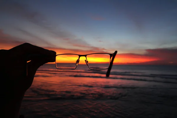 Günbatımı ve okyanus bir elinde gözlük sayesinde