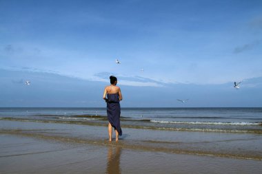 Baltık Denizi, kadın çıplak ayakla plaj ve feedi yürüyor
