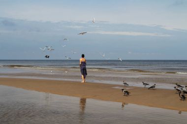 Baltık Denizi, kumsalda yürüyüş ve b besleme koyu saçlı kadın