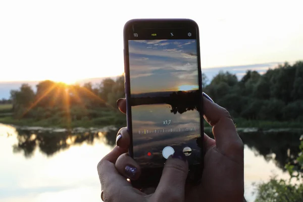Tangan wanita membuat foto matahari terbenam menggunakan zoom di smartphone — Stok Foto