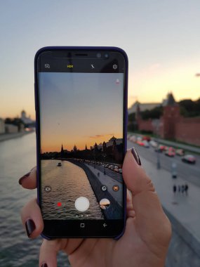 Kadın eli yapmak şehir resmini günbatımı smartphone. EY