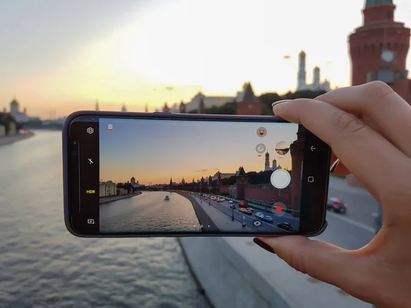 Mano femenina toma una foto en su teléfono inteligente ciudad puesta del sol Fotos De Stock