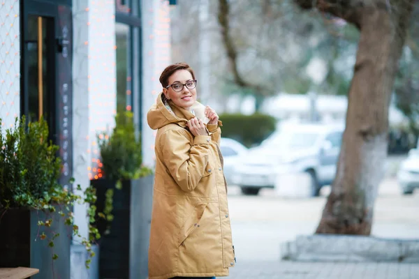 Young beautiful woman  in glasses, short fashionable hairstylein in office clothes, jacket, walking through the streets, spring walks