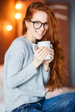 Noel oturuyor çay tutan genç kırmızı saçlı kız Oda dekore edilmiştir.