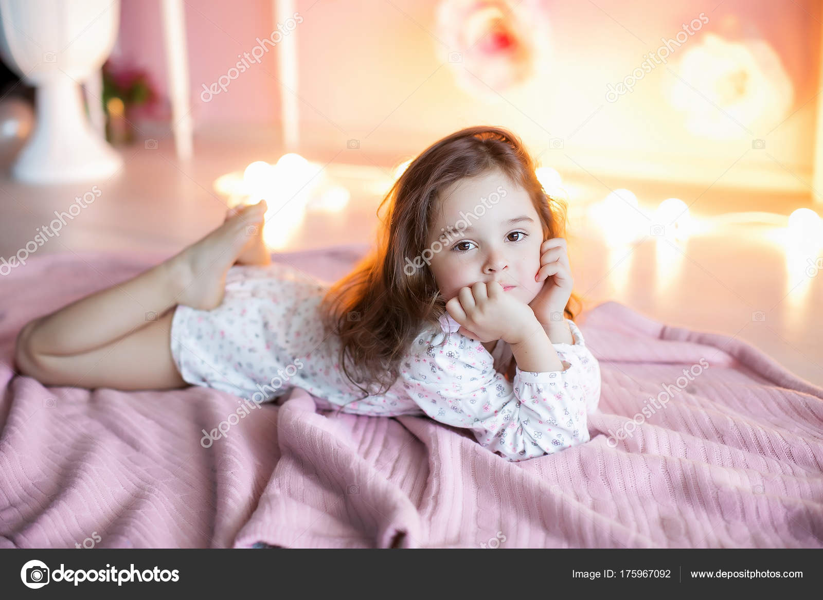 Niña Posando Acostada Sobre Cuadros Rosados Con Luces Fondo Foto de