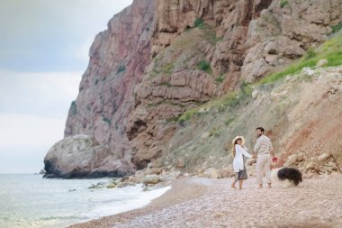 tüylü köpekle kumsalda yürüyen genç çiftin tam uzunlukta