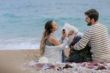 Hasır şapka ve sakallı adam eğleniyor genç kadın tüylü köpekle oynamayı