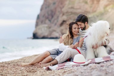 Genç çift ekose sahilde oturup tüylü köpek aşık 