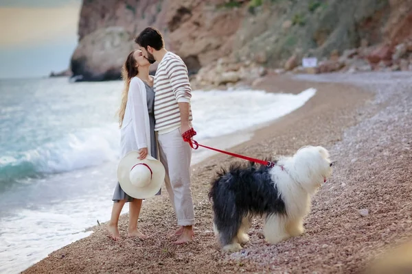 ヤング カップル立っているビーチでふわふわの犬とのキスの全長 — ストック写真