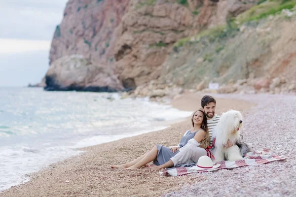 young happy couple resting with dog sitting on beach