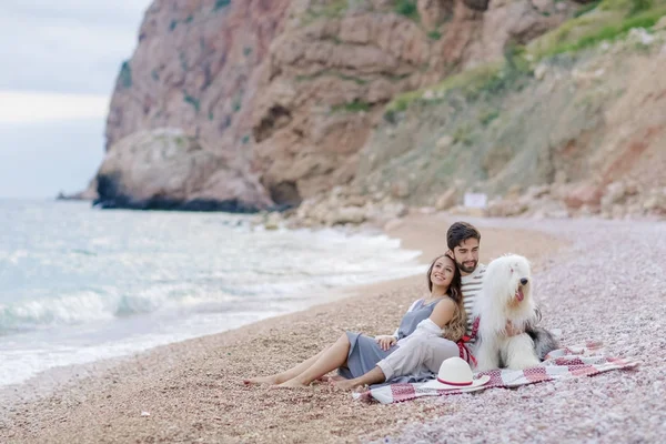 young happy couple resting with dog sitting on beach