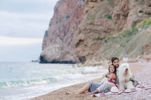 young happy couple resting with dog sitting on beach