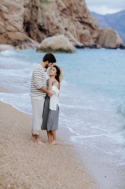 mutlu adam arka plan, tam uzunlukta cliff ve dağ ile yalınayak kumsalda üzerinde duran güzel onun gülümseyen kadın kucaklayan