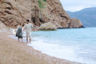 mutlu çift ıslak giysileri içinde deniz kıyısında çalışan el ele tutuşarak aşk